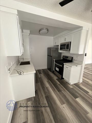 Hawthorne apartment for rent - a small kitchen with white cabinets and a stove and refrigerator